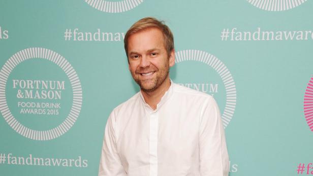 Ein Mann posiert vor einer Wand mit dem Logo der Fortnum & Mason Food & Drink Awards.