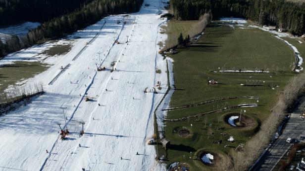 „Wexl-Spiel“ der Jahreszeiten. Links fahren Kinder Ski, rechts daneben wird im Motorikpark geklettert.