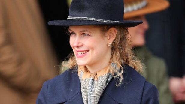 Lady Louise Windsor mit Hut und blauem Mantel lächelt.