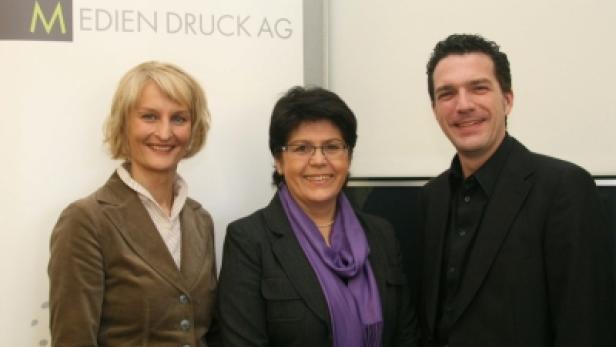 Drei Personen posieren vor einem Schild von Mediendruck AG.