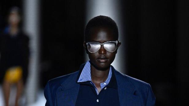 Ein Model präsentiert einen Preppy-Look mit Blazer, Poloshirt und Rüschenrock.