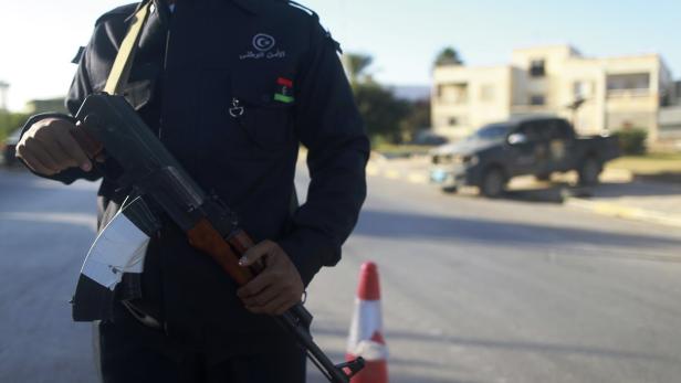 Ein Polizist in Uniform mit einem Gewehr auf einer Straße.