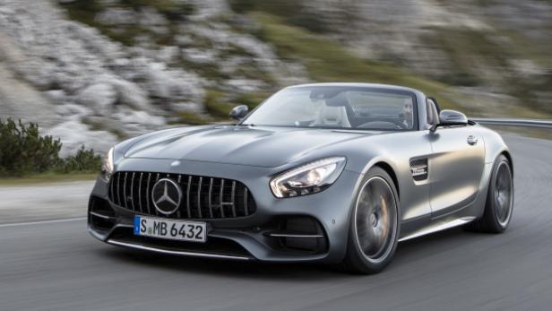 Ein grauer Mercedes-AMG GT Roadster fährt auf einer kurvigen Straße.