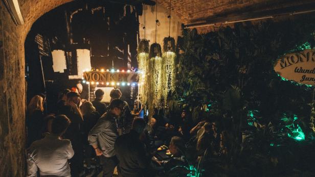 In einer Bar namens „Monkey“ sitzen und stehen viele Menschen.