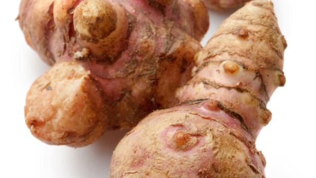 Drei Topinambur-Knollen liegen auf einem weißen Hintergrund.