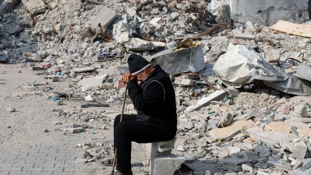 ein alter Mann sitz allein und traurig auf einem Trümmerhaufen