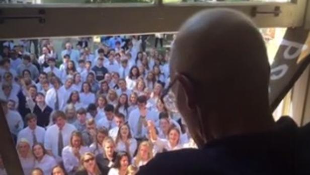 Eine große Gruppe von Schülern in weißen Hemden und Krawatten wird von einer Person gefilmt.