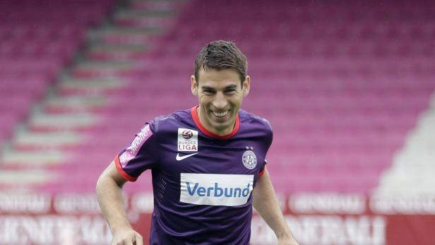 Ein lächelnder Fußballspieler im lila Trikot des FK Austria Wien.