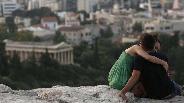 A couple embraces as they sit on a hill overlooking Athens near the archaeological site of the Acropolis in Athens June 27, 2013. Greek tourism revenues are expected to bounce back this year to pre-crisis levels, the industry said. The Mediterranean country has pinned its hopes on its sun-drenched beaches and ancient monuments to pull itself out of a deep recession. Tourism is the Greek economy&#039;s biggest cash-earner, accounting for about 17 percent of output. REUTERS/John Kolesidis (GREECE - Tags: SOCIETY TRAVEL BUSINESS)