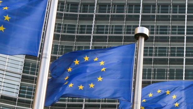Mehrere EU-Flaggen wehen vor einem modernen Bürogebäude.