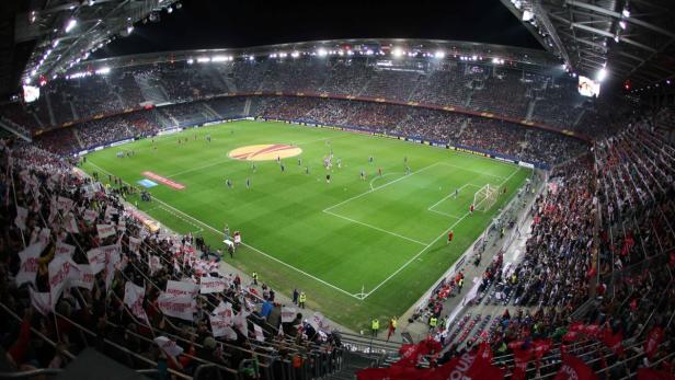 Ein Fußballspiel in einem vollbesetzten Stadion bei Nacht.