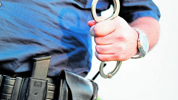 Polizei hält Handschellen in der Hand.