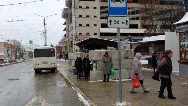 Menschen warten bei einer mit Beton verstärkten Busstation in Belgorod in Russland.