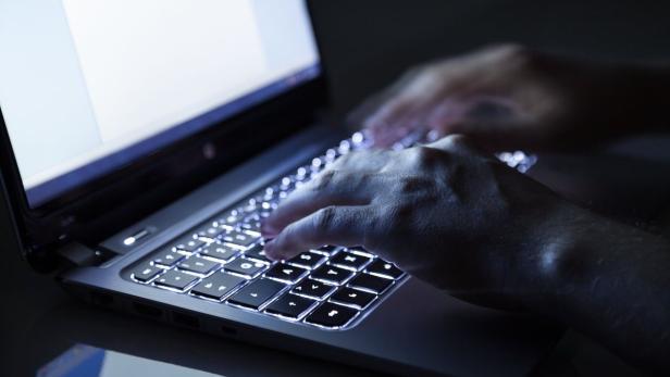 Eine Person tippt auf einem Laptop mit beleuchteter Tastatur.