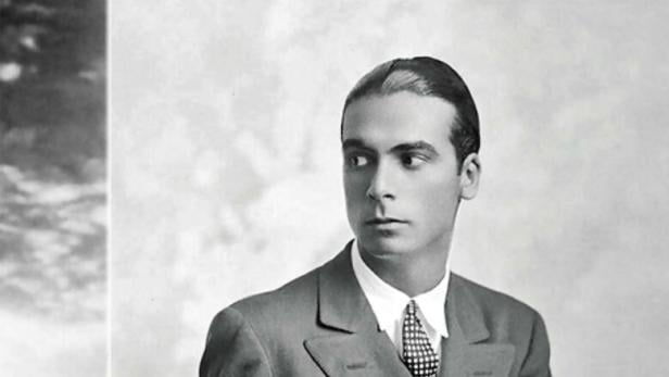 Ein Mann im Anzug sitzt und schaut zur Seite.