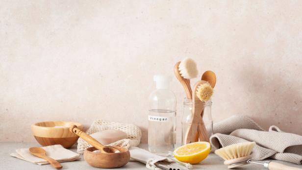 Verschiedene umweltfreundliche Reinigungsutensilien auf einer hellen Oberfläche.