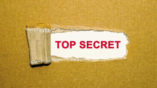 The text Top Secret appearing behind torn brown paper