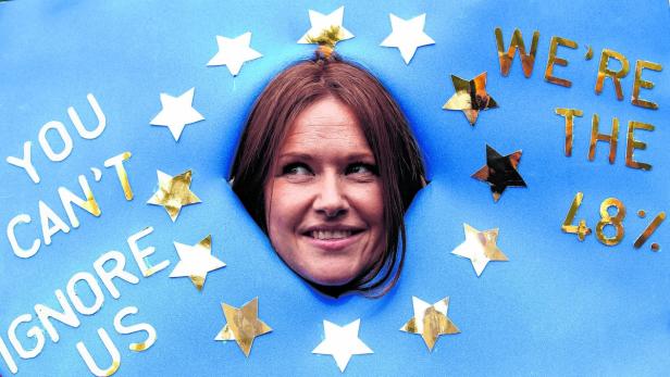 Eine Frau schaut durch ein Loch in einem blauen Banner mit der Aufschrift „You can't ignore us. We're the 48%“.