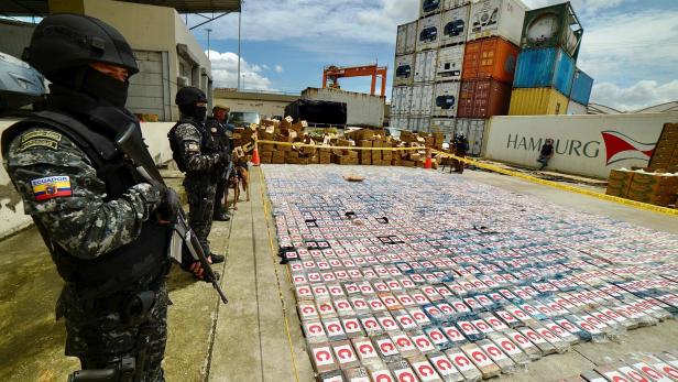 Kokainpäckchen liegen am Boden im Hafen aufgereiht und werdne von Soldaten bewacht