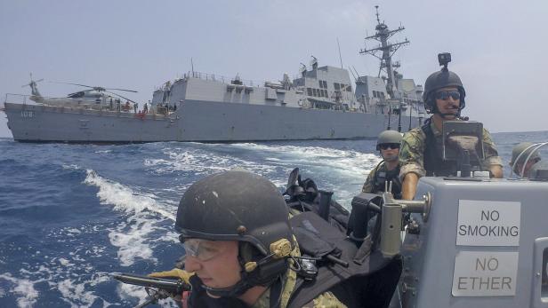 Marinesoldaten in einem Boot, dahinter ein amerikanisches Kriegsschiff