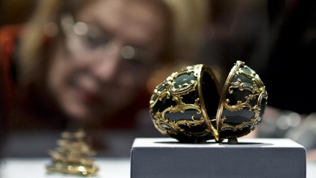 AUSSTELLUNG "DIE WELT VON FABERGE" IM KHM IN WIEN Eine Frau betrachtet ein geöffnetes Fabergé-Ei mit goldenen Verzierungen in einer Vitrine.
