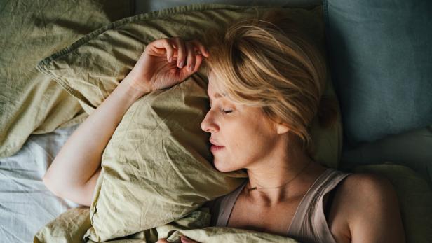 Frau schläft in seitlicher Position auf einem Kissen.