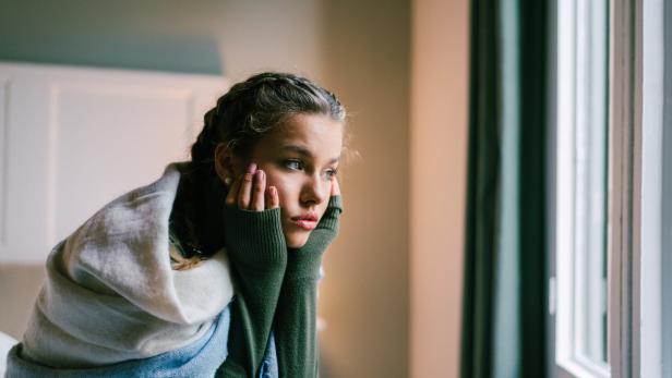 Mädchen sitzt auf dem Bett, enttäuscht und traurig.