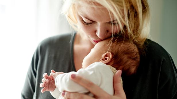 Eine Mama küsst ihr Baby auf den Kopf.