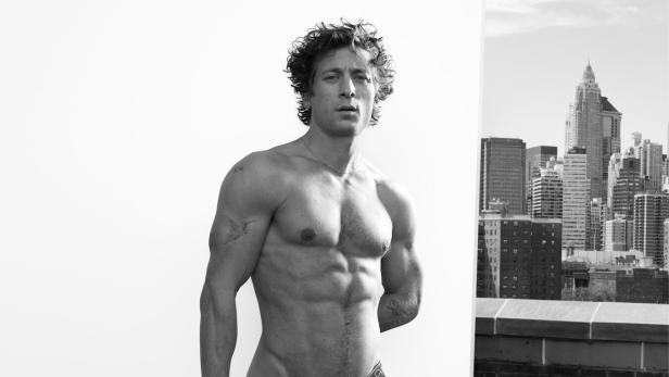 Ein muskulöser Mann posiert in Calvin Klein Unterwäsche vor einer Skyline in Schwarzweiß.