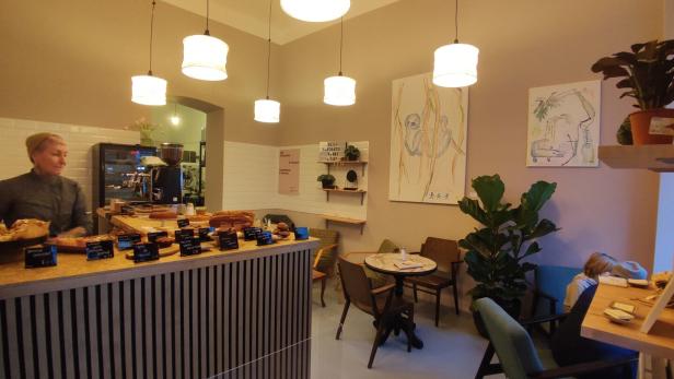 Innenansicht eines Cafés mit einer Theke voller Gebäck und Sitzgelegenheiten.