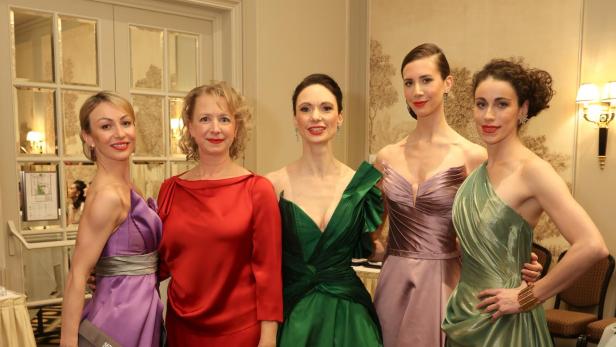 Fünf Frauen posieren in farbenprächtigen Abendkleidern für ein Foto.
