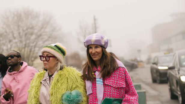 Zwei Frauen in farbenfrohen Outfits auf einer Straße.