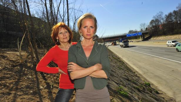 Zwei Frauen stehen neben einer Autobahn.