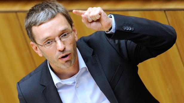 Ein Mann mit Brille gestikuliert mit erhobenem Zeigefinger.