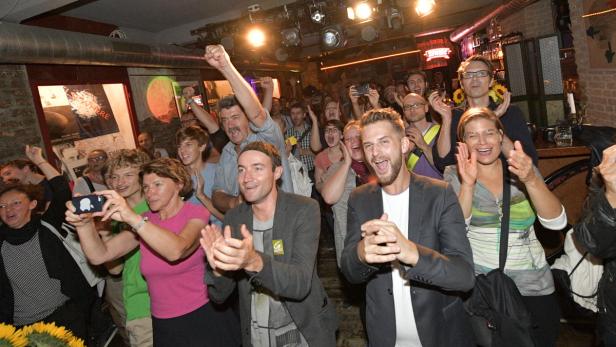 Eine Menschenmenge jubelt und klatscht in einem beleuchteten Raum.