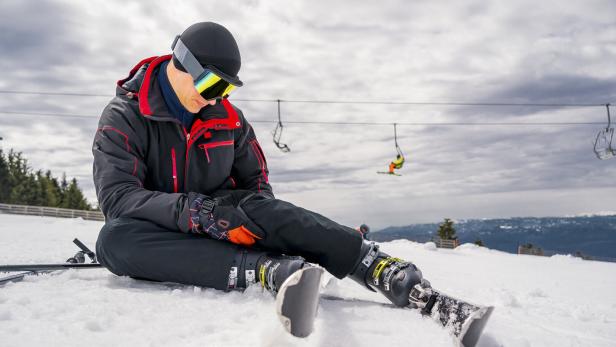 Ein Mann liegt auf einer Ski-Piste.