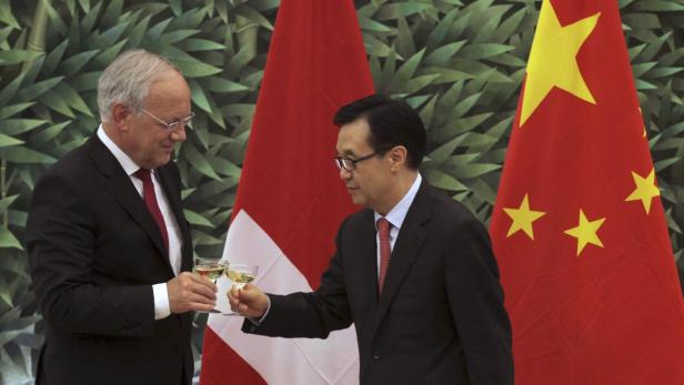 Chinese Commerce Minister Gao Hucheng (R) toasts with Swiss Economy Minister Johann Schneider-Ammann in front of the national flags of Switzerland (L) and China after signing a free-trade agreement at China&#039;s Ministry of Commerce in Beijing July 6, 2013. REUTERS/China Daily (CHINA - Tags: POLITICS BUSINESS) CHINA OUT. NO COMMERCIAL OR EDITORIAL SALES IN CHINA