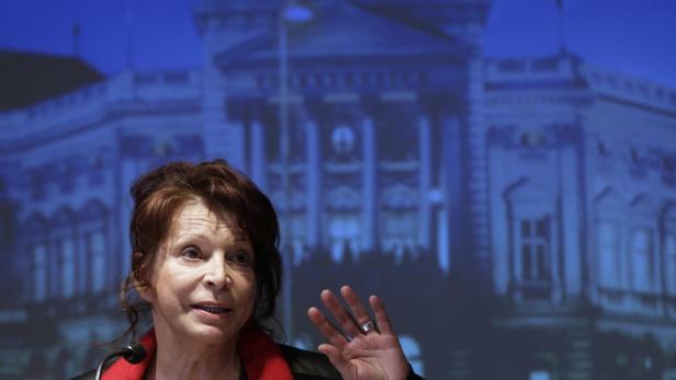 Eine Frau spricht vor einem verschwommenen Bild des Reichstagsgebäudes.