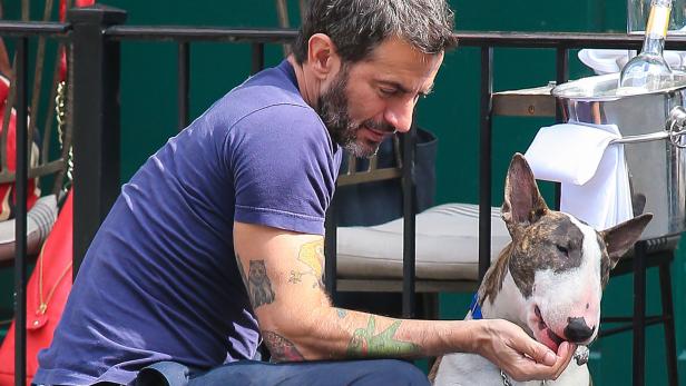 Ein Mann mit Tätowierungen streichelt einen Bullterrier.