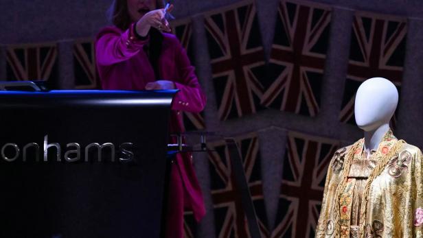 Bei Bonhams steht ein reich verziertes Gewand auf einer Schaufensterpuppe vor Union-Jack-Flaggen.