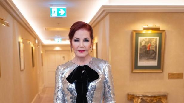 Priscilla Presley in einem silber-goldenen Paillettenkleid mit schwarzer Schleife.