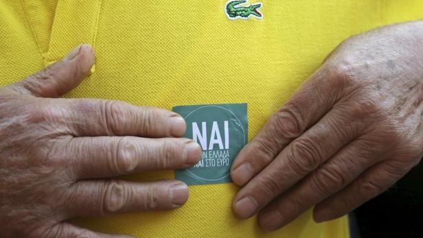 Eine Person mit einem „NAI“-Aufkleber („Ja“ auf Griechisch) auf einem gelben Lacoste-Polohemd.