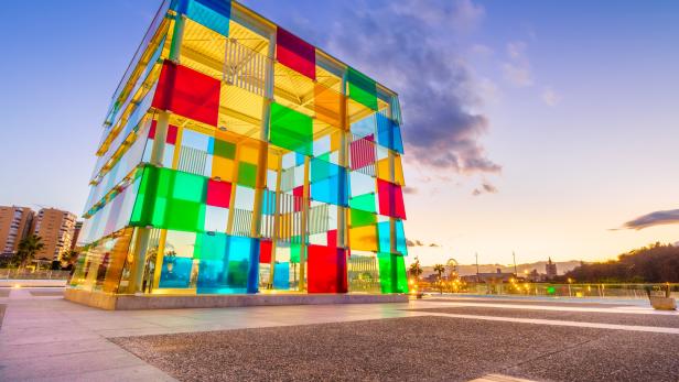 Der bunte Glaswürfel des Centre Pompidou Málaga bei Sonnenuntergang.