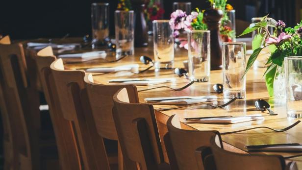 Ein gedeckter Holztisch mit Blumenvasen und Gläsern in einem Restaurant.