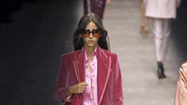 Eine Frau in einem pinkfarbenen Samtanzug auf einem Laufsteg.