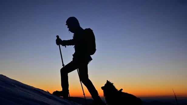 Wanderer mit Hund zu Sonnenaufgang im Almenland