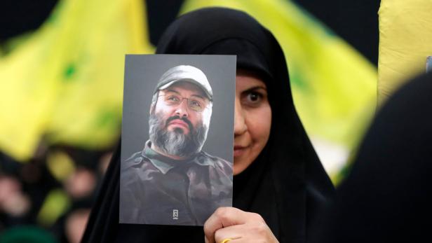 Frau hält ein Foto des Hisbollah-General Imad Mughniyeh in die Kamera