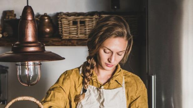 Eine Frau in einer Küche beim Einlegen von Gemüse in Gläser.