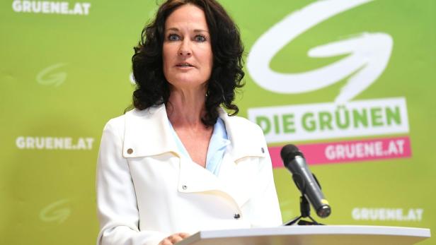 Eine Frau spricht am Rednerpult vor einem Hintergrund der Grünen Partei Österreichs.