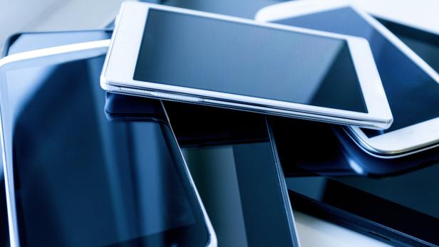 Ein Stapel von Smartphones und Tablets mit dunklen Bildschirmen.